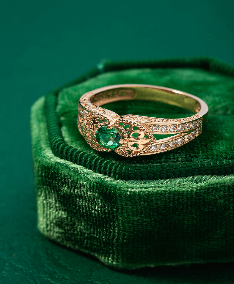 Gold ring with emerald and diamonds displayed.
