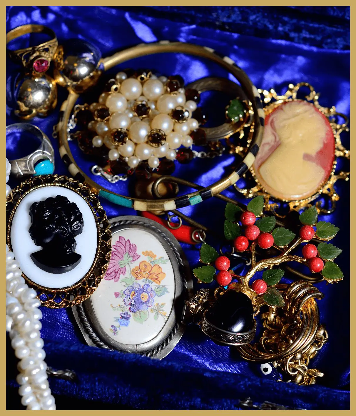 Assorted vintage jewelry on blue fabric.