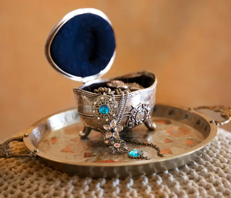 Intricately designed silver container with turquoise stones on a matching tray.