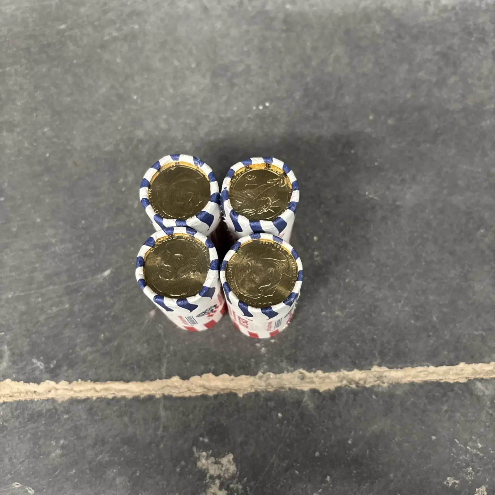 Four rolls of coins on concrete surface.