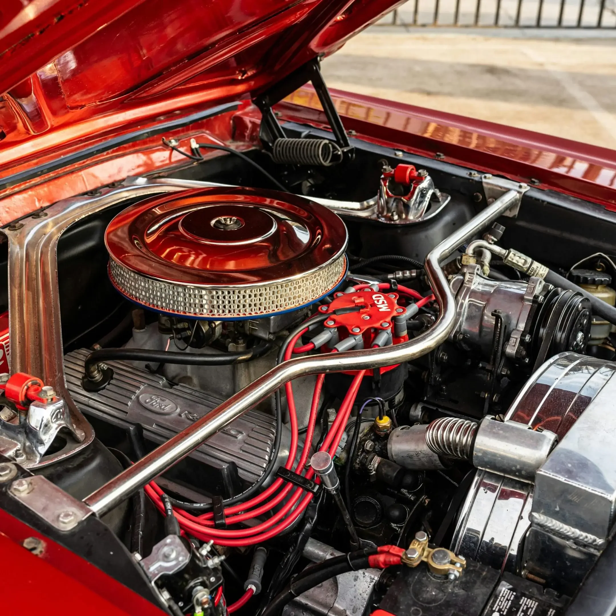Close-up of a classic car engine with red detailing and polished components.